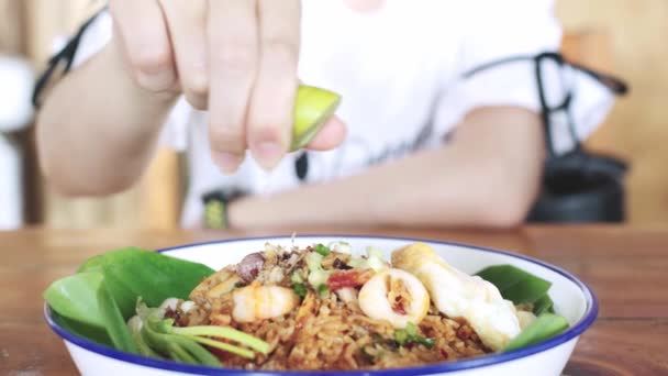 Hembra exprimir agua limón, lima, a los mariscos frescos deliciosos arroz frito con teste picante de deliciosa comida en Tailandia, comida tailandesa — Vídeo de stock