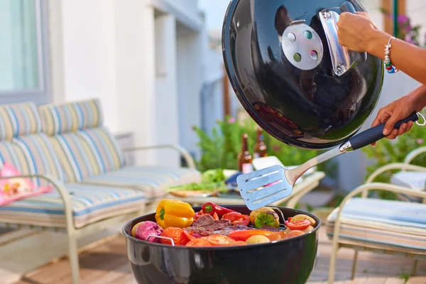Çeşitli lezzetli ızgara et biftek ile çeşitli sebzeler, kırmızı biber, domates, biber, kömürün üstünde el swapping etli - yuvarlak modern Barbekü üzerinde hafta sonu veya tatil kavramı