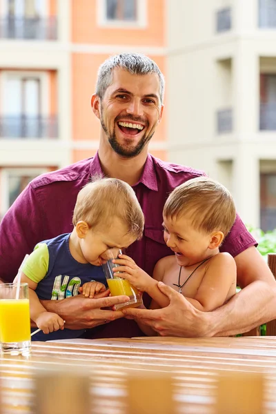 Happy father with his children  drinking orange juice — Stock Photo, Image