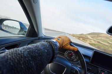 close up of Driver's hand in the leather glove in the modern luxury car interior when speeding