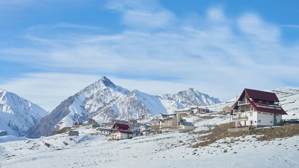 Modern mountains  ski resort with beautiful cottages with snowy peaks on the background in Georgia — Stok fotoğraf