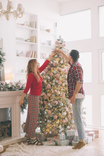 Joulukuusi koristelu nuori pari laittaa joulu pallot vihreä puu yhdessä — kuvapankkivalokuva