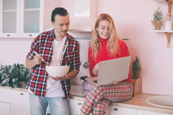 Portrait of a cheerful young couple cooking christmas meal together according to a recipe on a tablet computer — Stock Photo, Image