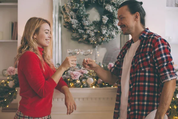 Young beautiful couple celebrating christmas at home in cozy clothes and drinking champagne — Stock Photo, Image