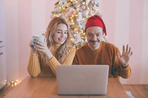 Happy young couple making video call with laptop, greeting their family with Christmas or New Year holidays. — Stock Photo, Image