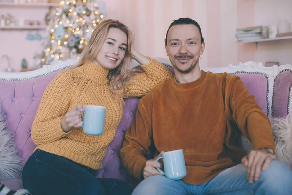 Portrait of a funny couple watching tv sitting on a couch in the living room at home in winter — Stock Photo, Image