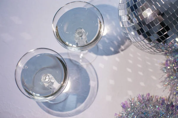 Copo de champanhe em um cupê com bola de discoteca e brilhos. Festa de Ano Novo, aniversário, dia das meninas ou outro evento de celebração — Fotografia de Stock