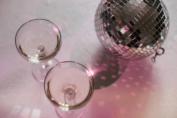 Copo de champanhe em um cupê com bola de discoteca e brilhos. Festa de Ano Novo, aniversário, dia das meninas ou outro evento de celebração — Fotografia de Stock