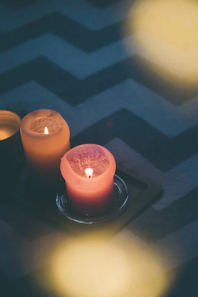 Aconchegante decoração de casa real, queimando velas na bandeja de madeira na pele de falso branco na cama — Fotografia de Stock