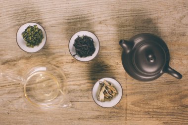 Ahşap arka planda çay seti. yeşil, siyah, kırmızı, beyaz çay ve çaydanlık