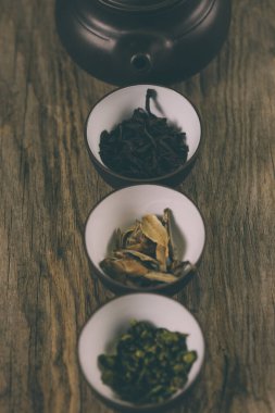 Ahşap arka planda çay seti. yeşil, siyah, kırmızı, beyaz çay ve çaydanlık