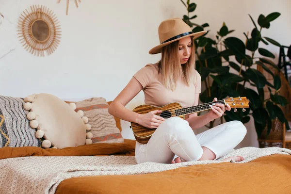 Mladý legrační hipster dívka baví a hraje na malé ukulele kytaru, zpěv a tanec. s kloboukem, radostí, pozitivní náladou. instagram live koncert Stock Obrázky