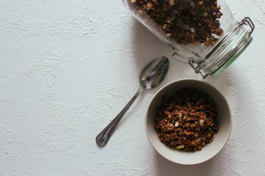 Kahvaltıda çikolatalı granola. Bir kavanoz, bir kase müsli ve bir bardak yoğurt.