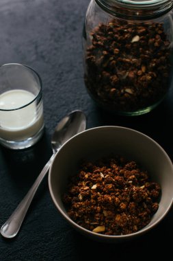Kahvaltıda çikolatalı granola. Bir kavanoz, bir kase müsli ve bir bardak yoğurt.
