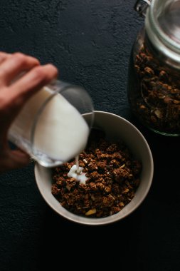 Kahvaltıda çikolatalı granola. Kavanoz ve üzerine bir kase müsli ve yoğurt döküldü.