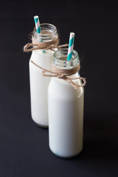 Two milk bottle with blue retro straw on black — Stock Photo, Image