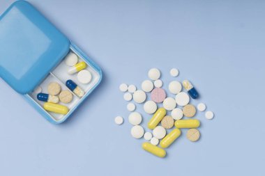 Mavi arka planda haplar olan hap kutusu. Tablet kutusu, rutin tedavi için vitaminler. Üst görünüm 