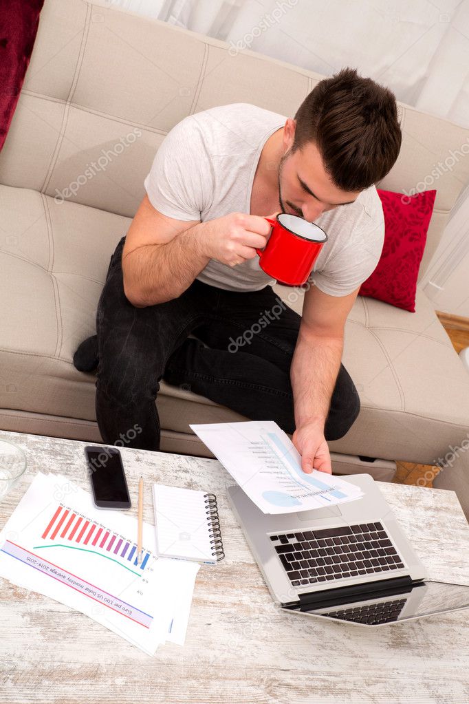 Businessman working at home meanwhile drinking coffee