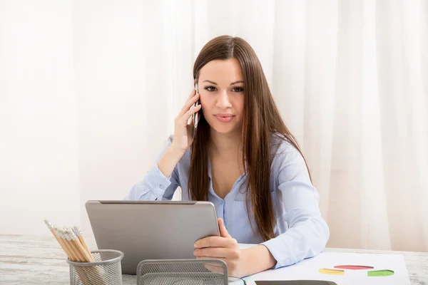 Trabalhando no escritório com o tablet e conversando por telefone — Fotografia de Stock