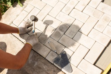 Üstat katman katman taş döşedi. Bahçe tuğlası kaldırımı. Kum temeli üzerine ev avlusunda beton döşeme döşeme