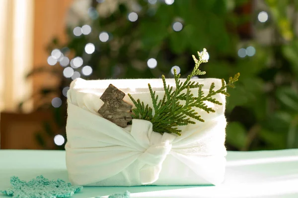 Um presente de Natal. Embalagem em materiais eco-friendly, tecido furoshiki. Bokeh, foco seletivo — Fotografia de Stock