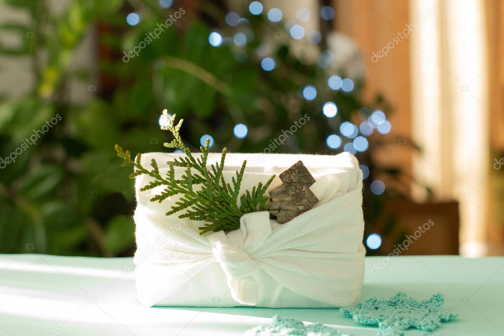 Christmas gift. Packaging in eco-friendly materials, furoshiki fabric. Bokeh, selective focus