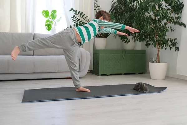 The boy goes in for sports at home online. The child does exercises in the room. — Stock Photo, Image