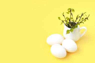 Boyanmamış beyaz paskalya yumurtaları ve dallarında yeşil yapraklar..