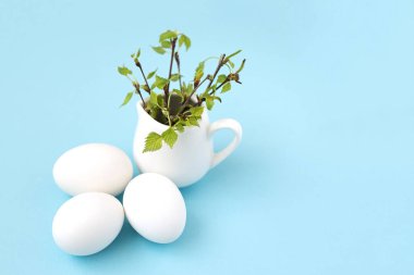 Boyanmamış beyaz paskalya yumurtaları ve dallarında yeşil yapraklar..