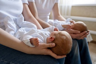 Yeni doğan tek yumurta ikizleri yatakta, ebeveynlerin ellerinde. Yaşam tarzı, çocukların duyguları. Kopyası olan bebek bebekler. Boşluk