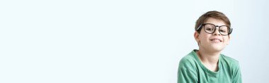 Yeşil tişörtlü ve gözlüklü şaşkın çocuk başını kaşımış. Boşluğu kopyala.