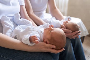 Yeni doğan tek yumurta ikizleri yatakta, ebeveynlerin ellerinde. Yaşam tarzı, çocukların duyguları. Kopyası olan bebek bebekler. Boşluk