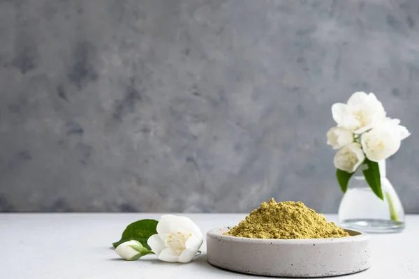 .henna powder for dyeing hair and eyebrows and drawing mehendi on hands on a gray cement pedestal with dried flowers or a white flower.