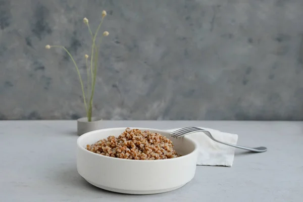 Tigela de trigo sarraceno em um fundo de concreto cinza em estilo minimalista. Conceito de alimentação saudável. — Fotografia de Stock