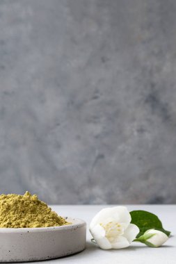 Saç ve kaş boyamak için kına tozu ve ellerinde kurumuş çiçeklerle gri çimento kaidesi ya da beyaz bir çiçek çizmek için mehendi..