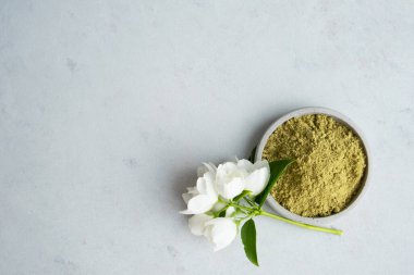 .Saç ve kaş boyamak için kına tozu ve ellerinde kurumuş çiçeklerle gri çimento kaidesi ya da beyaz bir çiçek çizmek için mehendi..