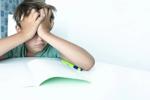 Szomorú fiú könyvvel házi feladatot csinál. Vissza a suliba. Boldogtalan iskolás fiú tankönyvekkel. Távolságtartó tanulás — Stock Fotó