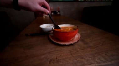Bir kase sıcak, baharatlı Tom Yum Kung çorbası pilav, mantar ve ahşap masada karides siyah kaşıkla karıştırılıyor. Çorba yerel restoranda servis edilir. Otantik popüler Tayland mutfağı. 