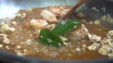 Tayland yemeği paslanmaz tavada kaynamış et suyu, baharat, bitki ve yumurta ile pişiriliyor. Geleneksel Asya deniz ürünleri pişirme. Yavaş çekim. Yakın çekim..