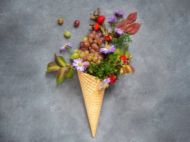Güz yapraklı dondurma külahı, gri arka planda gül kalçası ve çiçekler. Tebrik kartı. Uzayı kopyala, düz yat. Kavramsal fotoğraf, sonbaharın hediyeleri. Sonbahar sakin bir hayat.