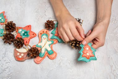 Çocukların elleri ev yapımı bir çelenk tutuyor. Zencefilli çörekler tuzlu hamurdan, konilerden yapılır. Hafif arkaplan. Noel için ev yapımı dekorasyon.
