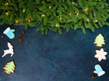 Mavi arka planda kıvırcık zencefilli kurabiye ve ladin dalları. Noel ağaçları, kar taneleri, geyik figürleri. Noel kartı. Yıldız anason yıldızları, tarçın. Düz yatıyordu. 