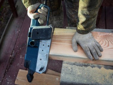 Öğütücü makineli bir katılımcının elleri. Uçan talaşlar, ahşap tahta. Bir profesyonelin işi. Ahşap. Ahşap endüstrisi.