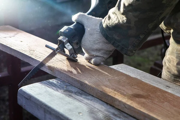 Hands of a joiner with a electric saw. Wooden board. The work of a professional. Woodwork. Woodworking industry.