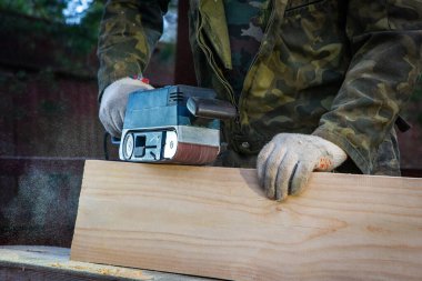 Öğütücü makineli bir katılımcının elleri. Uçan talaşlar, ahşap tahta. Bir profesyonelin işi. Ahşap. Ahşap endüstrisi.