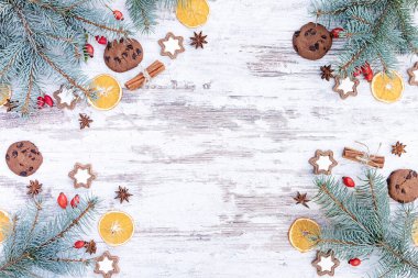 Noel kutlamaları ve davetiyeler için geleneksel atmosferik Noel arkaplanı. Mavi ladin dalları, kurutulmuş portakallar, yeni yılın tasarım şablonu için geleneksel semboller olarak zencefilli kurabiye.. 