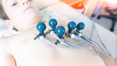 Yıllık terapi muayenesi sırasında bir çocuğun göğsüne elektrokardiyogram uygulamak için profesyonel tıbbi ekipman. Okul çağındaki çocukların EKG odasında kalp hastalığı teşhisi.