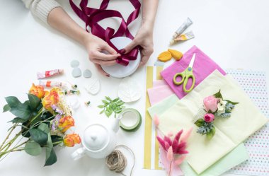 Kız yapay çiçeklerin ürünlerini topluyor. Sahte çiçek, buket, saç tokası ve mücevher üretimi için çiçekçi tasarımcının iş yeri..