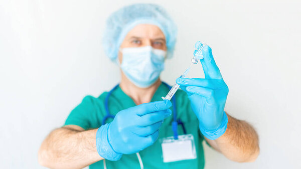 Strict doctor with a syringe is preparing to make an injection close-up on a light background. Fear of injections. The concept of fear of doctors and vaccinations. Coronavirus vaccination concept.
