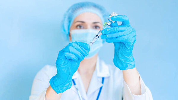 An exciting photo of a doctor preparing to inject with the Covid-19 coronavirus vaccine. The doctor holds the syringe and medicine at eye level. The concept of planned immunization of the population.